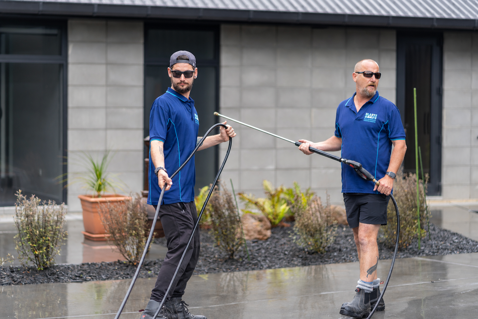 Jeff on the left and Pete on the right, holding concrete-cleaning equipment outside a house in Whangārei.